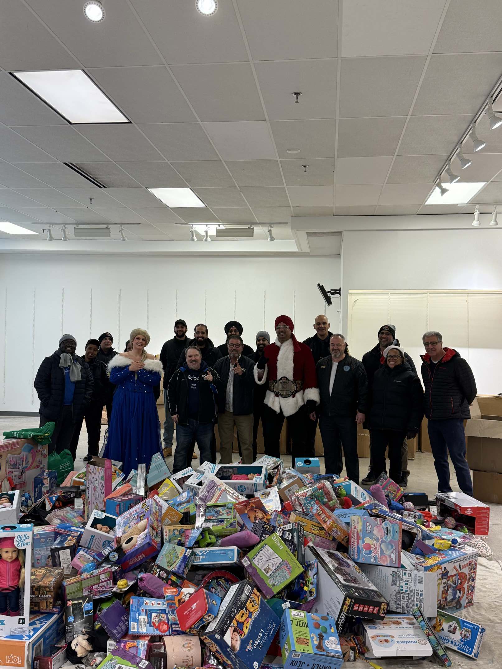 Pat Fortini with volunteers and a large pile of donated toys at a holiday toy drive